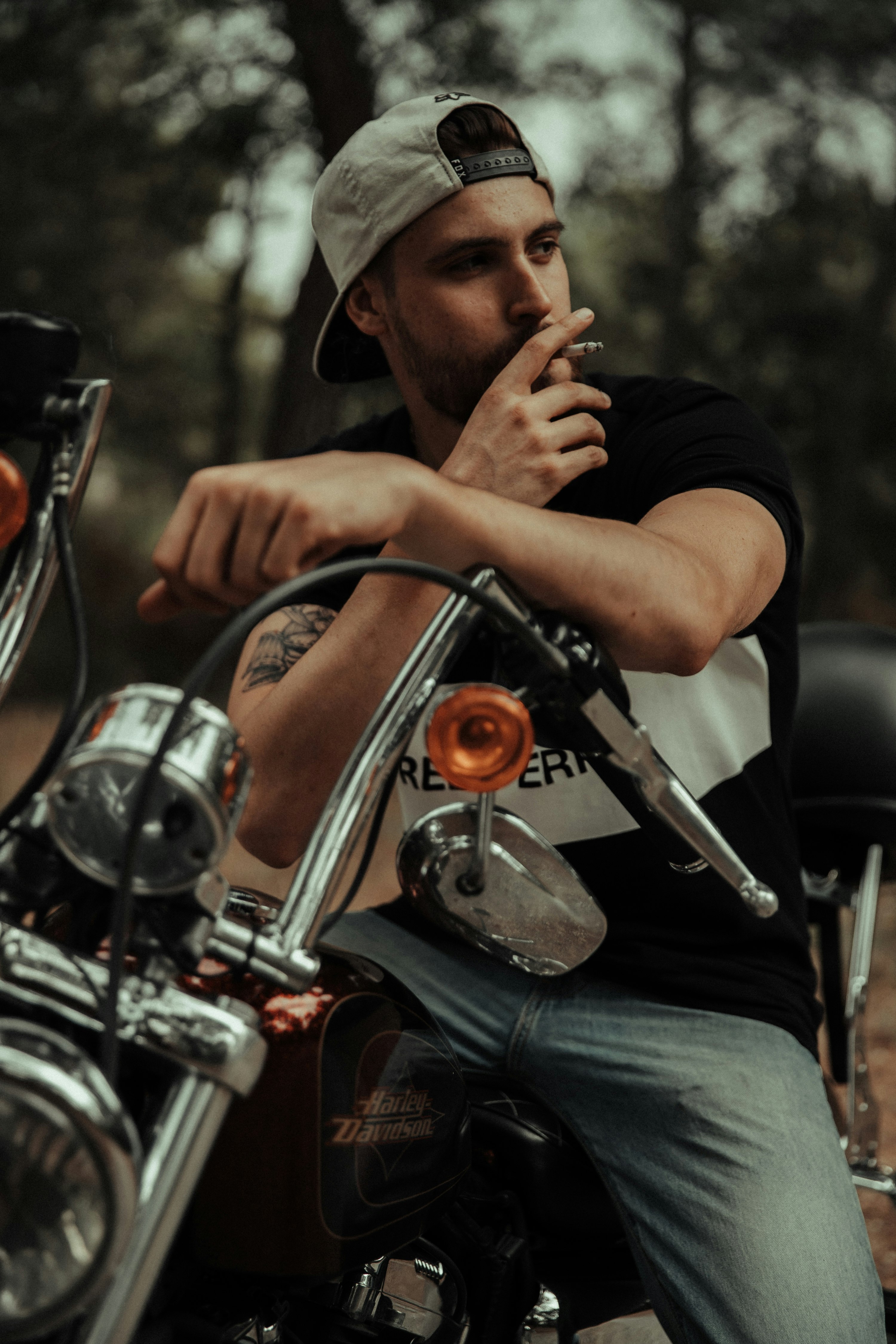 man in black t-shirt and blue denim jeans sitting on red motorcycle